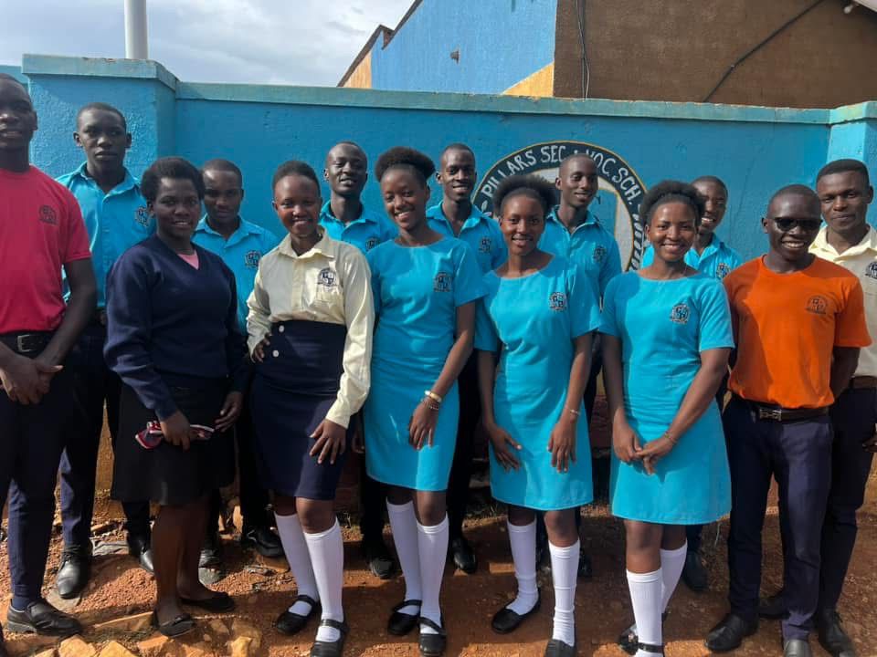Pillars Secondary and Vocational School students gathered in front of the school sign