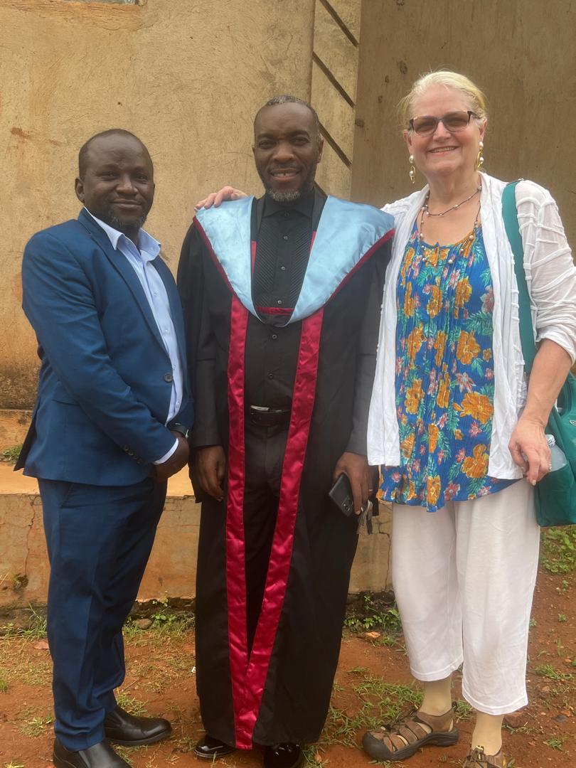 Graduate standing with PACM leaders and a visiting supporter